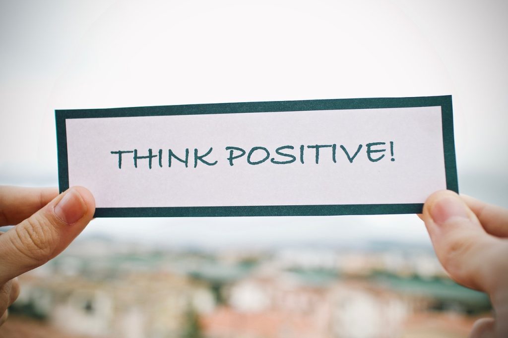 A person holding a card showing 'Think positive'