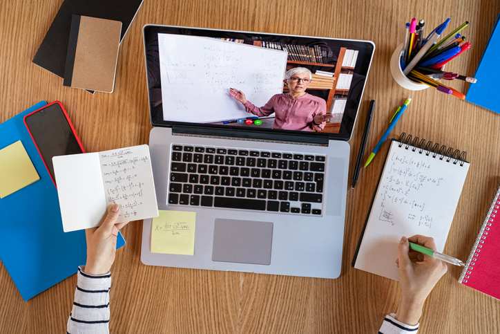 A person attending an online lecture and taking notes 